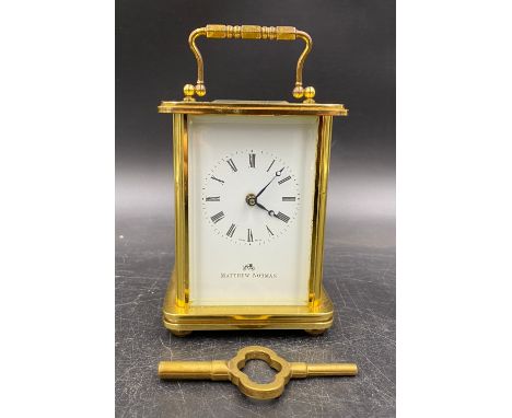 A Swiss brass-cased carriage clock for Matthew Norman Retailers, London with visible escapement and white dial set with Roman