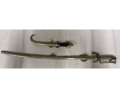 A white metal sword with decorative hilt and scabbard (Tulwar ?) together with a short white metal sword with wooden handle. 