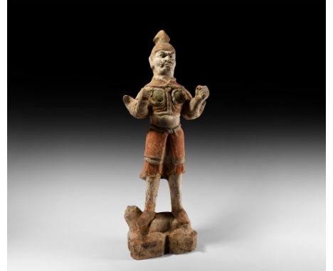 Tang Dynasty, 618-907 AD. A substantial ceramic guardian or warrior figure modelled standing, trampling an animal lying on a 