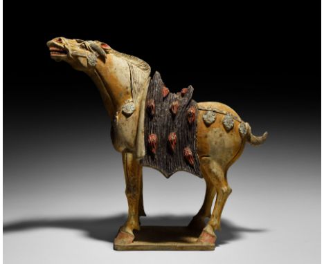 Tang Dynasty, 618-907 AD. A ceramic statuette of a horse standing on a rectangular base; the neck straight and extended, head