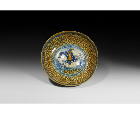 Early 16th century AD. A ceramic maiolica bowl with dimpled centre and broad raised rim; pattern of concentric scales surroun