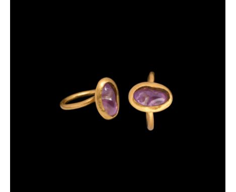 14th-15th century AD. A gold finger ring with slender hoop and pie-dish bezel, inset irregular amethyst; possibly Eastern wor