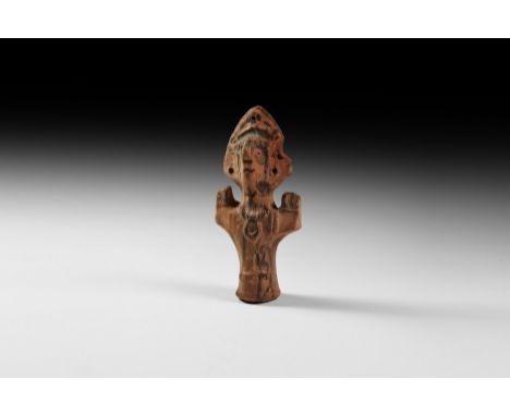 5th-8th century AD. A ceramic votive figure of a saint with cylindrical body, triangular headdress, pinched face and arms hel