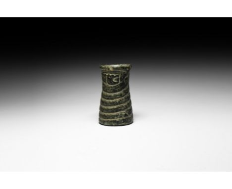 3rd millennium BC. A carved stone jar with waisted cylindrical body, everted rim and flat base, the body of a serpent coiled 