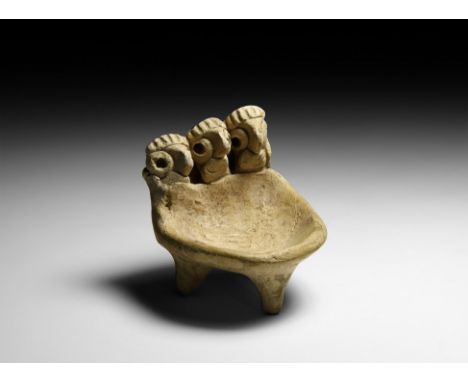 2nd-1st millennium BC. A ceramic lamp formed as a D-shaped tripod dish with a row of three heads to one edge; legs conical in
