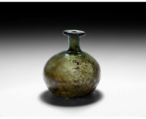 3rd-4th century AD. A substantial glass bottle with asymmetrical globular body, narrow neck, broad rolled rim, ovoid mouth an
