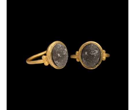 3rd-4th century AD. A gold finger ring with dished cell to the bezel, four granules flanking the attachment points, inset aqu
