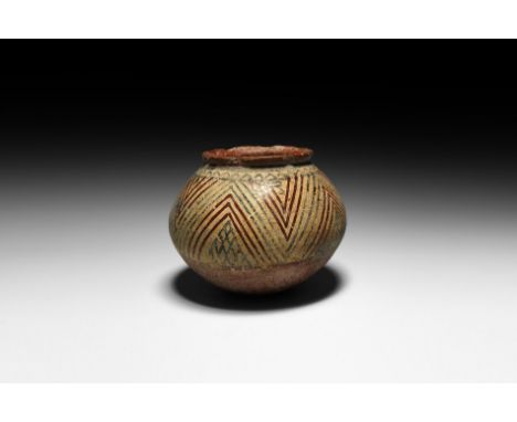 1st millennium BC. A carinated ceramic jar with everted rim, decorated with painted interlocking red and black; concentric ch