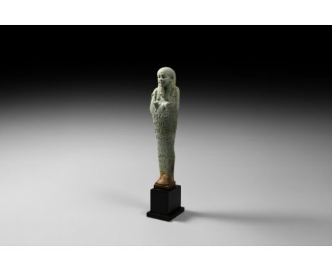 30th Dynasty, 380-343 BC. A substantial pale green glazed composition shabti with tripartite wig and false beard holding agri