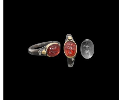 1st century BC-1st century AD. A silver ring with tapering D-section hoop and gold oval-shaped bezel, holding a garnet caboch