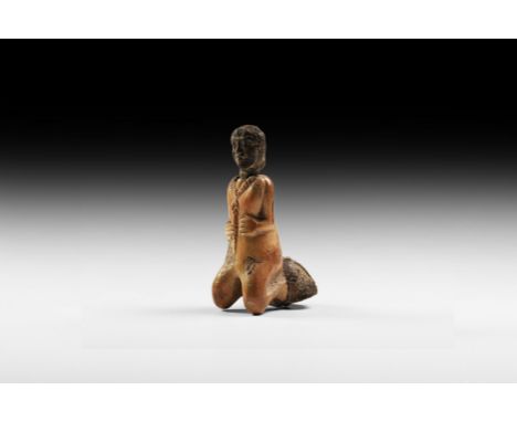 1st millennium AD. A carved bone kohl pot formed as a kneeling figure wearing a segmented necklace and holding an arrow to th