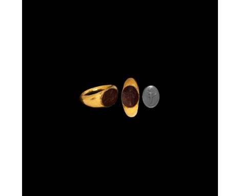 1st-2nd century AD. A gold hollow-formed finger ring with inset carnelian gemstone, intaglio figure of Salus standing, holdin