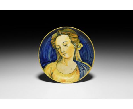 17th century AD. A ceramic maiolica dish with lustrous glaze, low flared foot, depicting the bust of a woman on a blue field 