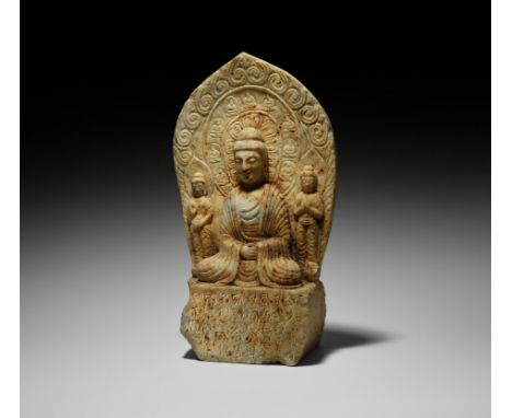 Sui Dynasty, 581-618 AD. A carved marble statue presenting Buddha seated on a rectangular plinth flanked by two standing atte