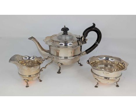 An Edwardian silver bachelor's three-piece tea service, each piece having a wavy rim to a banded lower body, raised on cast p