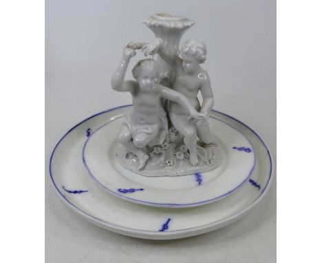 A Meissen blanc de chine porcelain candlestick, in the form of a seated putti before a tree trunk, height 19cm, together with