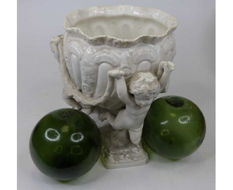 A Spode white glazed pottery jardiniere upon three figural putti supports, height 26cm, and two green glass balls (3)