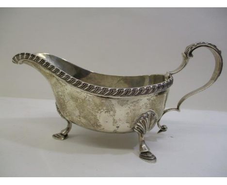 A 1930s silver sauce bowl by William Hutton &amp; Son, Birmingham 1938 with a gadrooned border and scrolled handle, on steppe
