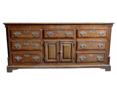 Early 19th century oak dresser base, rectangular top with decorative cross banding, seven mahogany cross banding drawers with