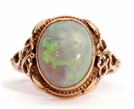 Late 19th/early 20th century opal ring, the cabochon oval shaped opal 12 x 10mm collet set between ornate pierced scroll shou