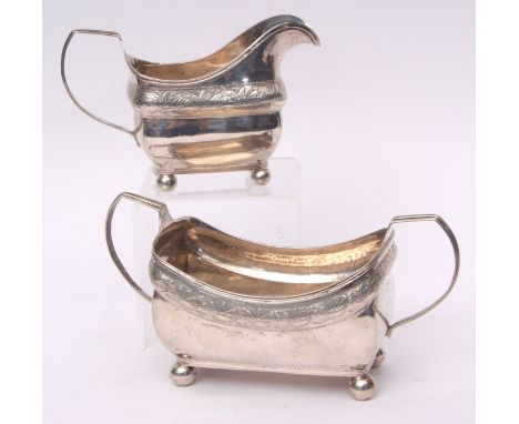 George III Irish sugar basin and milk jug, each of open rectangular form with reeded handles and each raised on four ball fee