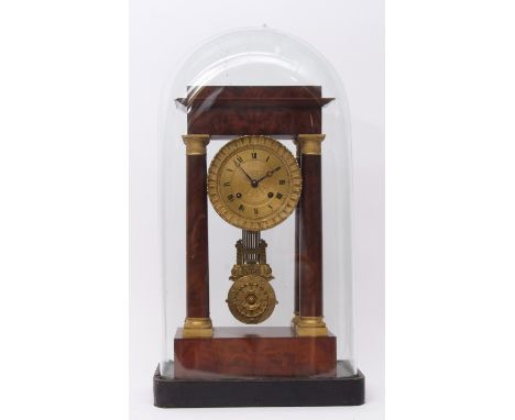 Early 19th century French flame mahogany and gilt brass mounted portico clock, the plinth shaped case supported on four gilt 