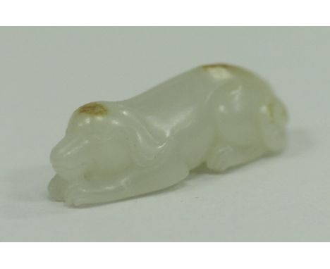 A Chinese carved jade figure of a recumbent dog, 4 cm long CONDITION REPORTS Has general wear and tear to include surface scr