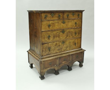 An 18th Century walnut chest of two short on three long graduated drawers upon a base of three drawers with arched apron to f