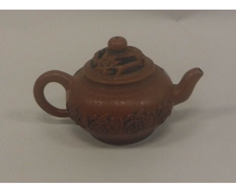 A Chinese Yixing teapot, the reticulated cover of branch and floral design, the main body decorated in relief with floral spr