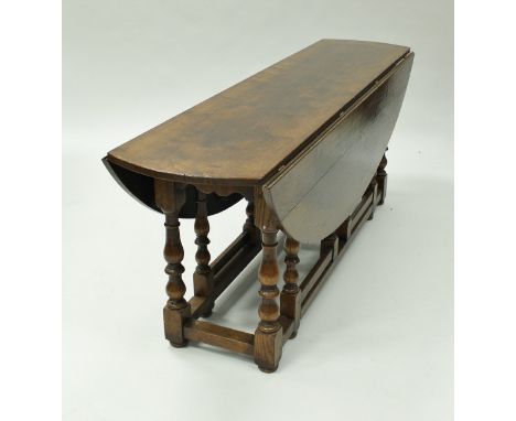 A oak wake table in the 18th Century manner, the oval drop-leaf top raised on twin gate-leg baluster turned and ringed suppor