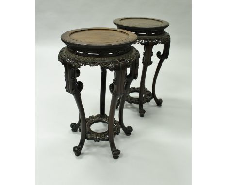 A pair of 19th Century Chinese rosewood urn stands of typical form, the circular dished tops above pierced frieze with scroll