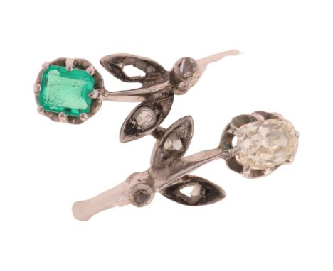 An 18ct white gold emerald and diamond crossover ring, floral design set with 0.5ct oval old-cut diamond and octagonal step-c