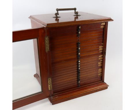 A Victorian mahogany microscope slide cabinet, brass carrying handle with glazed panelled door enclosing 25 drawers, some con