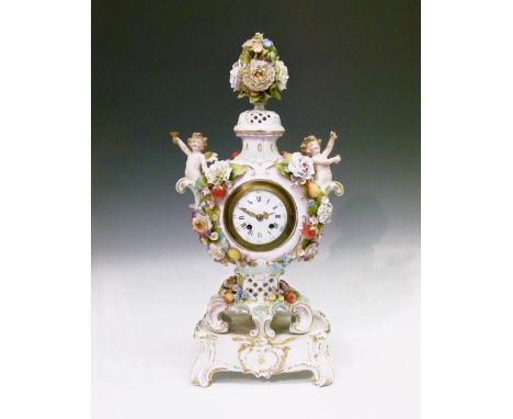 Late 19th/early 20th Century Continental porcelain mantel clock, of vase form surmounted by 'Deutscheblumen' over winged putt