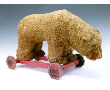 Large early 20th Century golden mohair bear (possibly Steiff), on a red wooden frame with wheels, 38cm x 58cm Condition: Loss