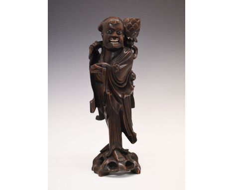 Early 20th century Oriental carved hardwood figural candlestick, modelled as a robed figure holding a ruyi septre and oversiz