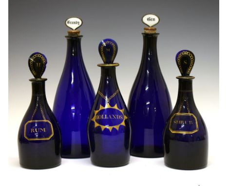 Five 'Bristol' blue glass decanter bottles, the two largest with stoppers for Gin and Brandy, two smaller with gilt labels fo