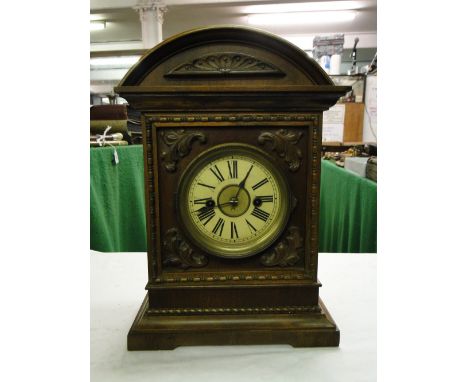A German 2-train mantel clock in carved wood case with foliate designs.