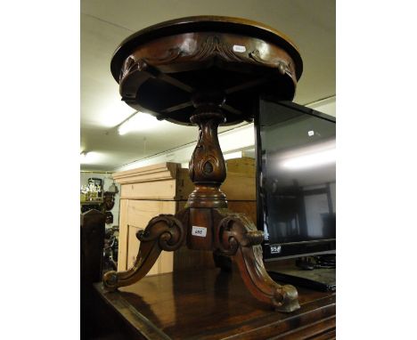 A reproduction carved mahogany tripod table.