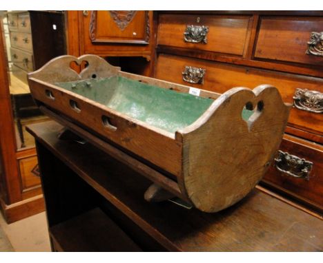 A stained wood trough in the form of a crib with metal liner.