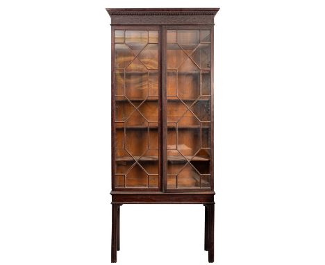 A George III mahogany and glazed bookcase on stand, late 18th century; with moulded and dentilled cornice above a blind fretw