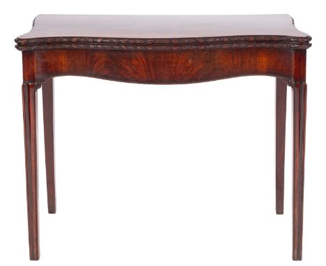 A George III mahogany serpentine front card table, early 19th century; the hinged top with foliate and ribbon carved edging; 