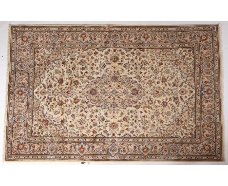 A Kashan carpet, the ivory Arabeque field with a central cartouche pole medallion, enclosed by a main beige palmette and scro