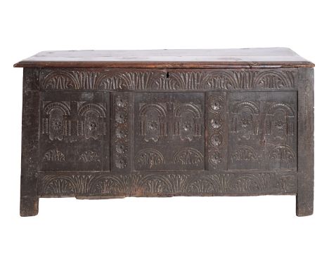 A Jacobean oak coffer, circa 1675; the hinged cover with moulded edges; the front with relief carved frieze of foliate filled