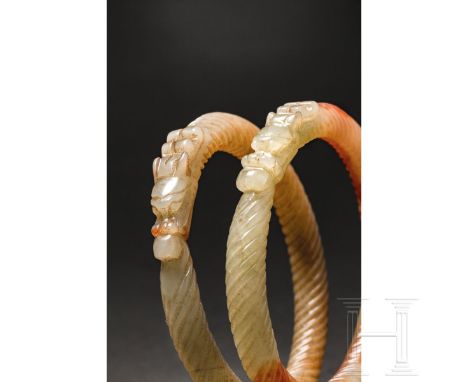 Zwei Jadeit-Armreife, China, 20. Jhdt.  Weiße, seladonfarbene Armreife mit rot-bräunlichen Einschlüssen. Jeweils in Form eine
