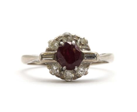 A white gold ruby and diamond cluster ring, with an oval mixed cut ruby, claw set, with a baguette cut diamond at each side a