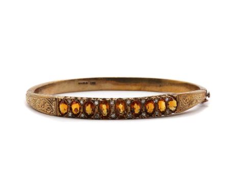 A 9ct gold citrine and diamond bangle, a row of graduated oval mixed citrines, with eight cut diamond set points, claw set, t