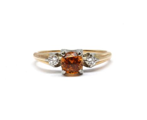 A gold orange zircon and diamond three stone ring, with a round mixed cut orange zircon, with a brilliant cut diamond at each