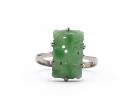 A white gold carved jade ring, a rectangular carved pierced jade, claw set, to tapered shoulders and a plain shank, tested as