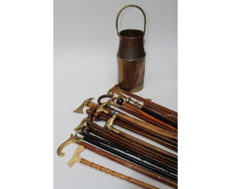 An early 20th century copper and brass churn, containing a collection of eighteen walking sticks and canes, largely reproduct